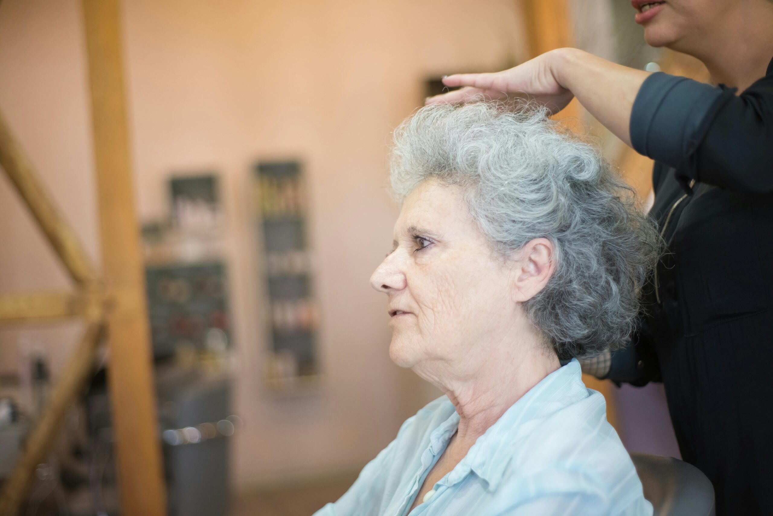 Senior woman gets a haircut at a cozy salon, showcasing personal grooming and care.